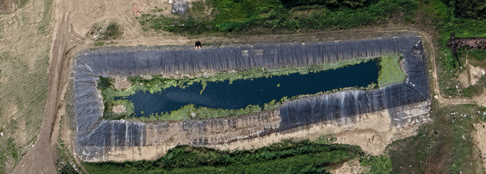 Aerial close-up of the lined leachate containment pond at the Virden Landfill, showing the synthetic liner and water surface.